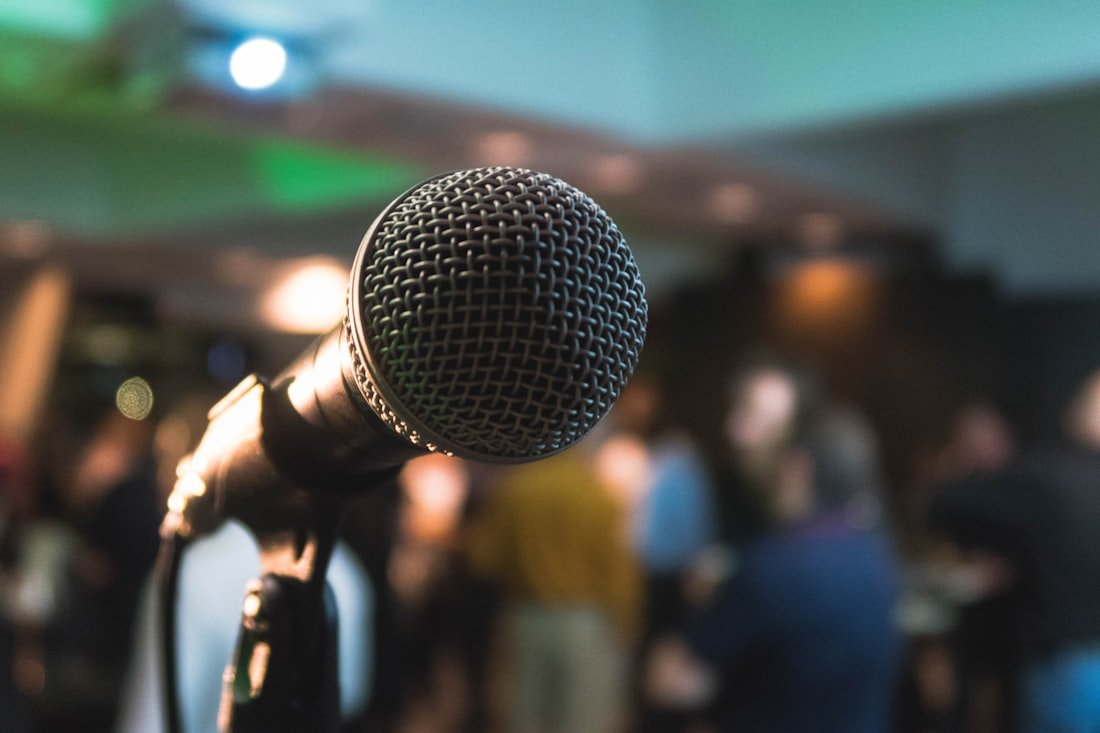 A microphone on stage in front of a full community event audience
