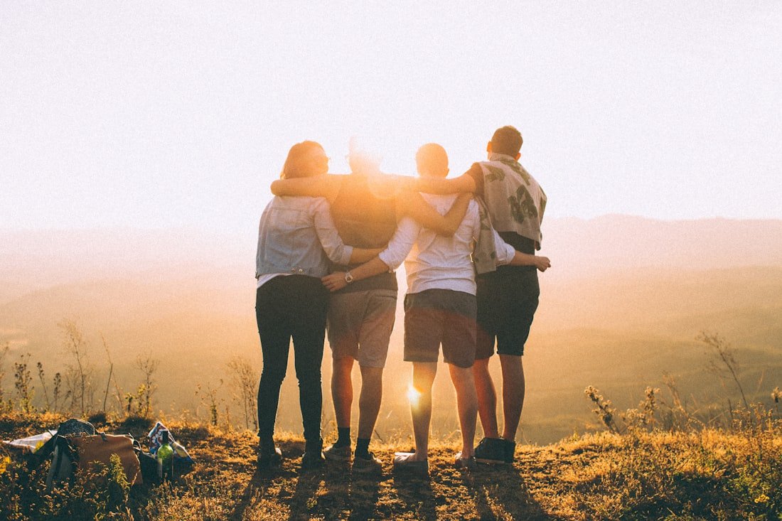 Friends with arms around each other at sunset